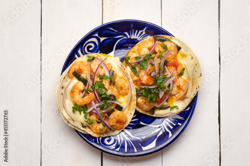 Mexican food. Shrimp tacos with melted cheese and poblano pepper called gobernador on white background. photo