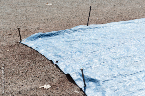 blue tarpaulin with anchor spikes covering the pitcher's mound