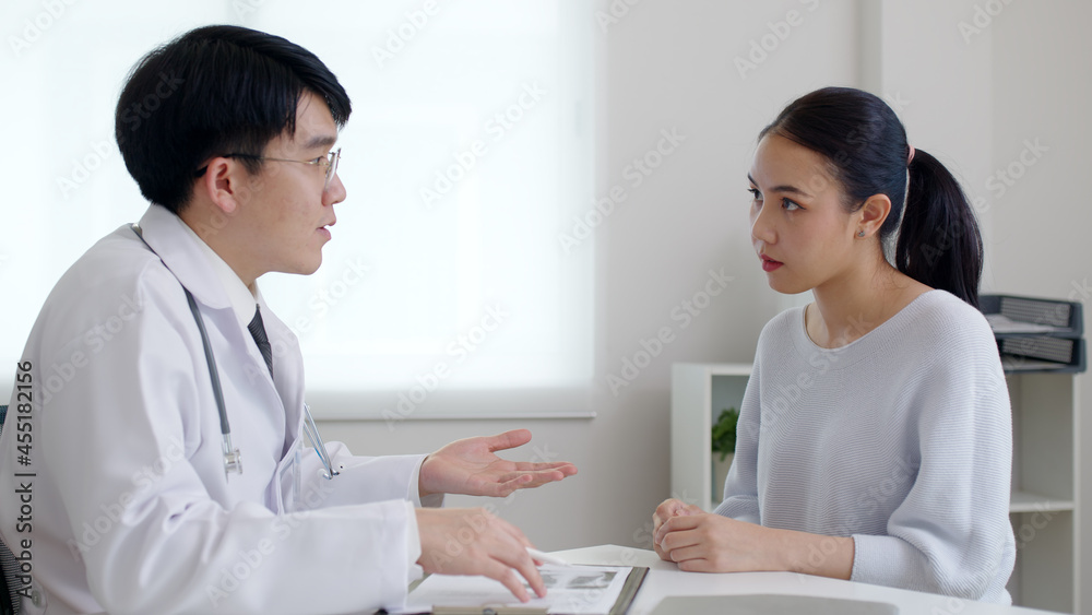 Friendly medic service people or asia male help talk discuss of medical exam record test result at clinic office desk. Young sad serious stress woman visit, follow , listen, see doctor at hospital. Friendly medic service people or asia male help talk discuss of medical exam record test result at clinic office desk. Young sad serious stress woman visit, follow , listen, see doctor at hospital.