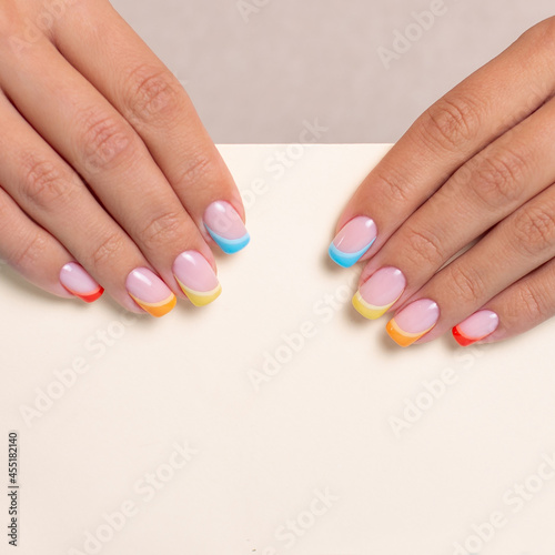 Beautiful female hands with colourful manicure nails with rainbow design