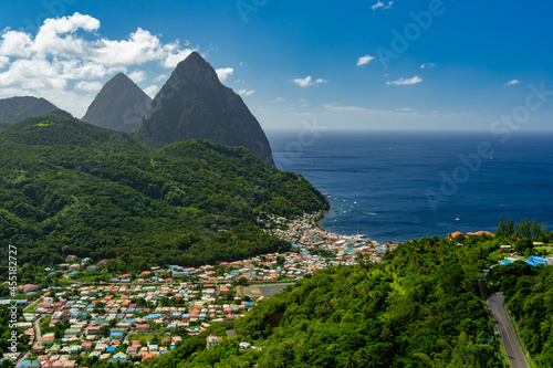 Soufriere, St Lucia from an overlook with the world famous Pitons in the background and beautiful blue Caribbean waters and a partly cloudy day.
