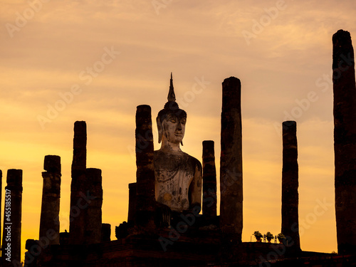 Amazing scenetic of silhouette of Wat Mahathat Temple in the precinct of Sukhothai Historical Park with big buddha statue on golden sunset sky background, a UNESCO World Heritage Site in Thailand.