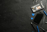 Damaged smartphone and repair tools on black background, flat lay. Space for text