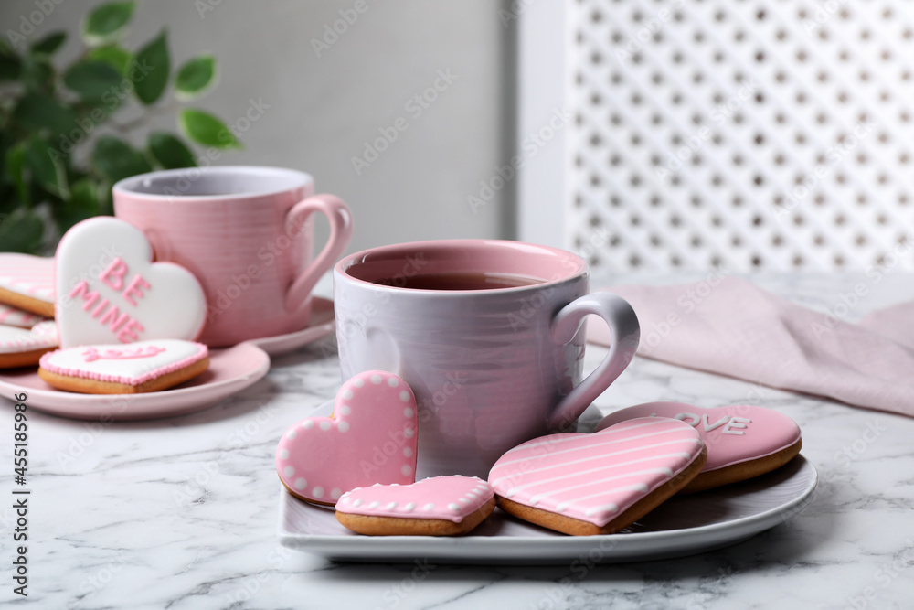 Delicious heart shaped cookies and cup of tea on white marble table Delicious heart shaped cookies and cup of tea on white marble table