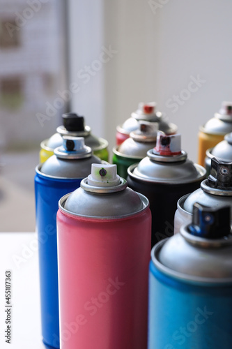 Cans of different graffiti spray paints on table, closeup