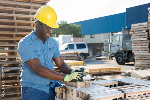 Male african worker checking quantity of bricks in warehouse of building materials