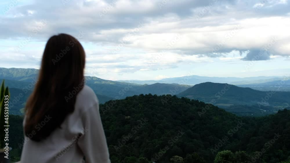 Blurred rear view of a female traveler looking at a beautiful mountains view Blurred rear view of a female traveler looking at a beautiful mountains view