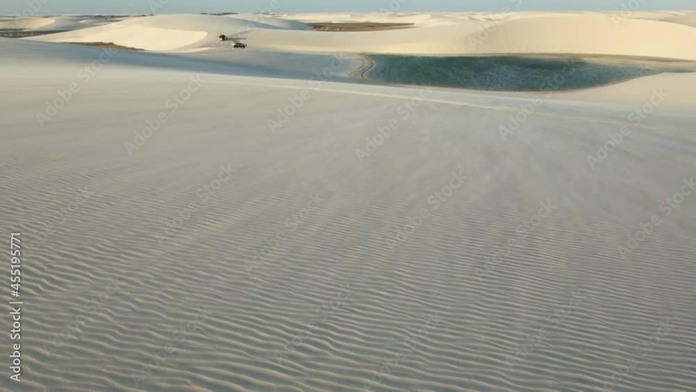 wind blowing over textured dunes, carrying off sand. oasis lagoon on backgroung. desert landscape wind blowing over textured dunes, carrying off sand. oasis lagoon on backgroung. desert landscape