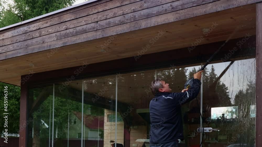 Man cleaning walls and floor with high pressure power washer. Washing terrace wood planks and cladding walls. Man cleaning walls and floor with high pressure power washer. Washing terrace wood planks and cladding walls.