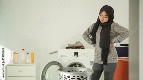 young asian woman upset to see dirty clothes basket at home photo