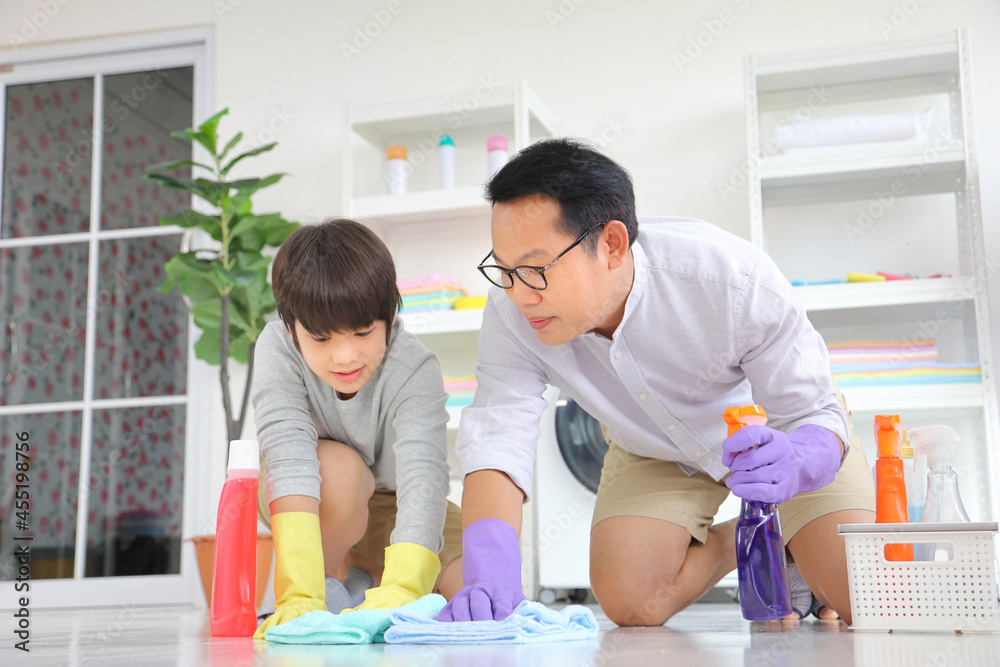 Asian father and son help each other to clean the floor for daily routine chores and housekeeping Asian father and son help each other to clean the floor for daily routine chores and housekeeping