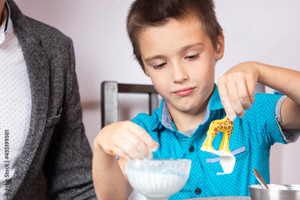 Chemistry education and training concept. Close-up of a boy and his dad making a home experience, making a non-Newtonian liquid from starch and water Chemistry education and training concept. Close-up of a boy and his dad making a home experience, making a non-Newtonian liquid from starch and water