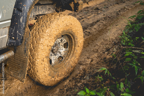Part of the muddy off-road wheels On a muddy road in the evergreen forest adventure concept forest tourism concept