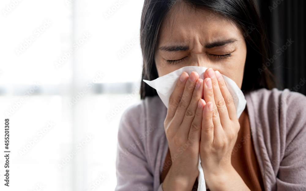 Young Asian women cover their mouth and nose with tissues during the flu, coughing and sneezing to prevent spreading the virus. Concept of health care and medicine Young Asian women cover their mouth and nose with tissues during the flu, coughing and sneezing to prevent spreading the virus. Concept of health care and medicine