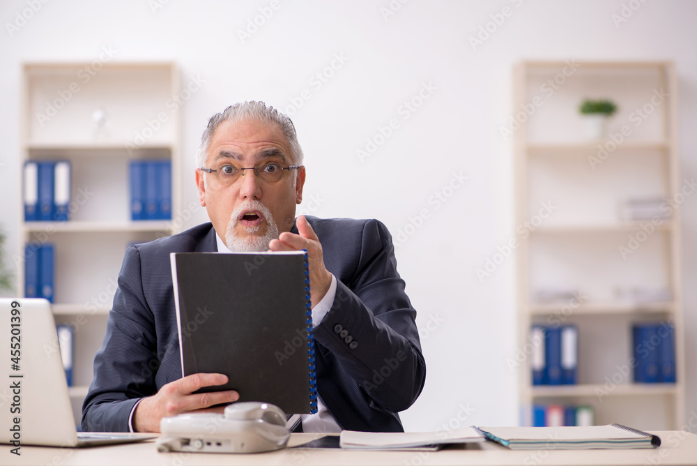 Old male employee working in the office Old male employee working in the office