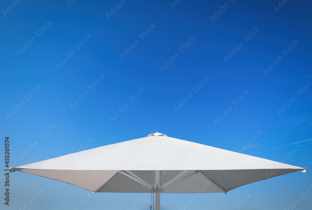 White beach umbrella against blue sky on sunny day