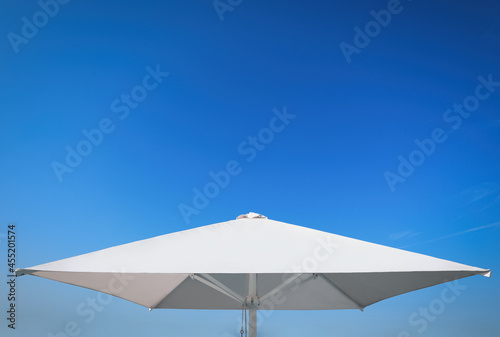 White beach umbrella against blue sky on sunny day