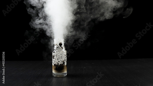 Potassium Permanganate Hydrogen Peroxide Decomposition Reaction. Smoke effect from the chemical reaction of mixing KMno4 and H2O2. Dangerous experiment on black background. photo