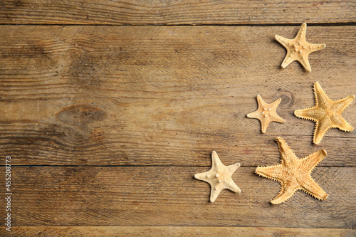 Beautiful sea stars on wooden background, flat lay. Space for text