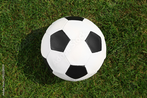 Football ball on green grass, top view