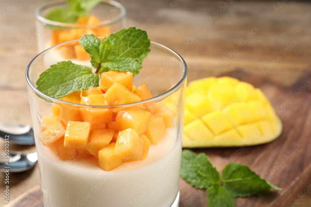 Delicious panna cotta with mango in glass dish on table, closeup Delicious panna cotta with mango in glass dish on table, closeup