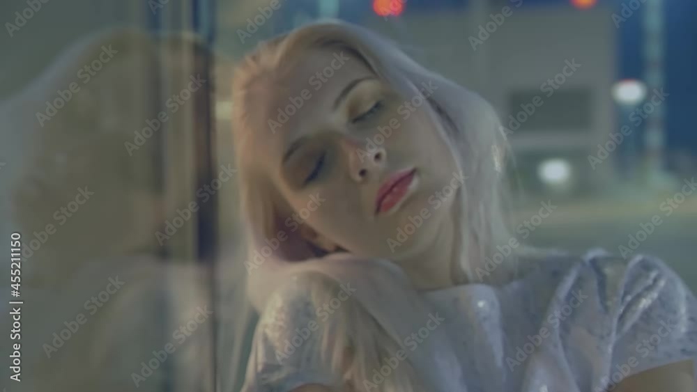 Portrait of a young blonde woman next to a display case against a backdrop of lights with a passing focus from blur to sharpness Portrait of a young blonde woman next to a display case against a backdrop of lights with a passing focus from blur to sharpness
