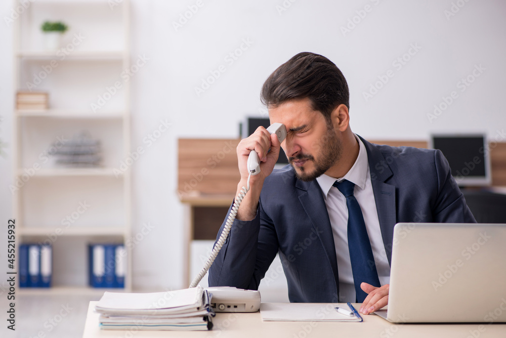 Naklejka premium Young male employee sitting at workplace