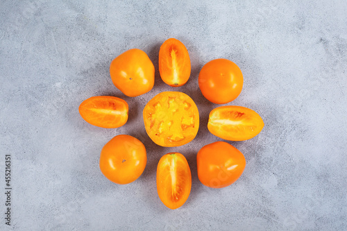 Ripe fresh yellow orange tomatoes on light gray background.