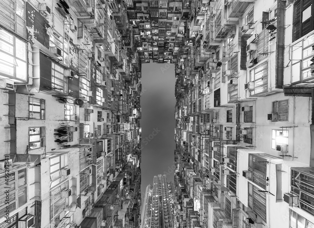 Exterior of crowded residential building in Hong Kong city at night. Building abstract background