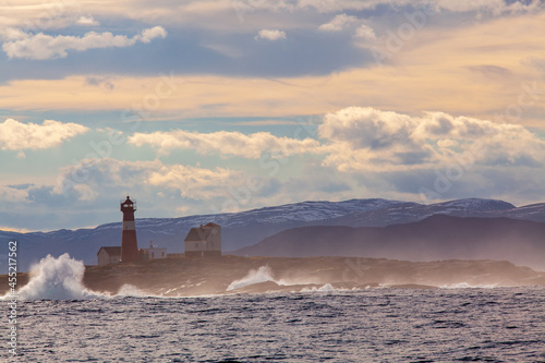 Beautiful seascape with light house in Norway. Colorful sky and mountains in background. photo