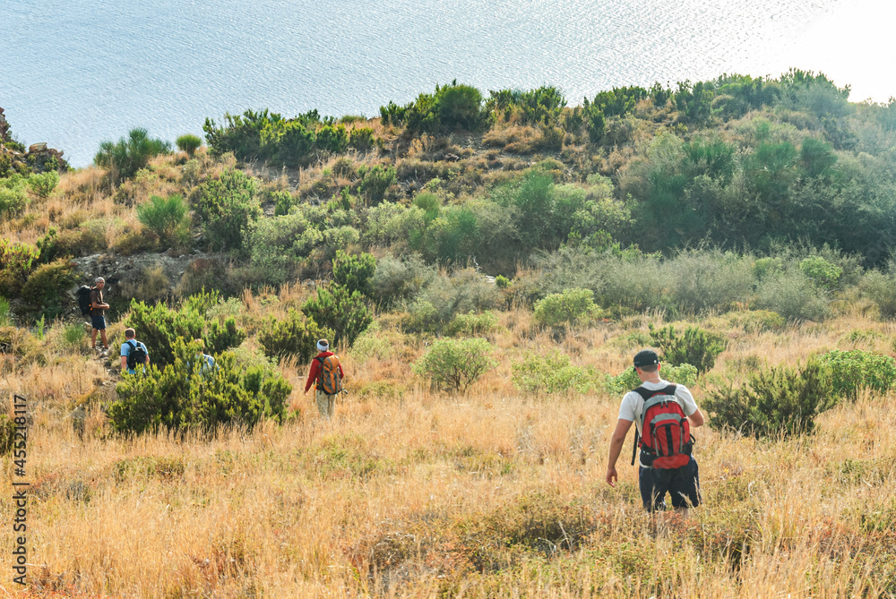 Obraz premium Wandergruppe unterwegs in der hügeligen Maccia-Landschaft rund um Lipari-Stadt 