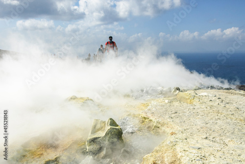 Wanderer mit Mundschutz durchquert Schwefeldampfwolken am Krater des Vulcano 