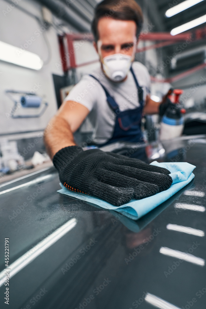 Hand pressing cloth to automobile surface while cleaning