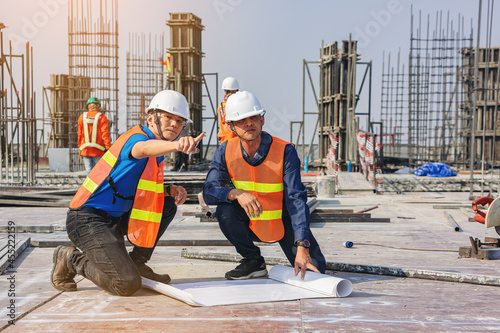 Slika na platnu Structural engineer and foreman worker with blueprints discuss, plan inspecting for the outdoors building construction site