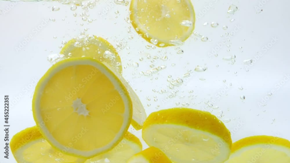 Slow Motion of fresh yellow lemon slices falling into water splash on white background, Vegetables for health.