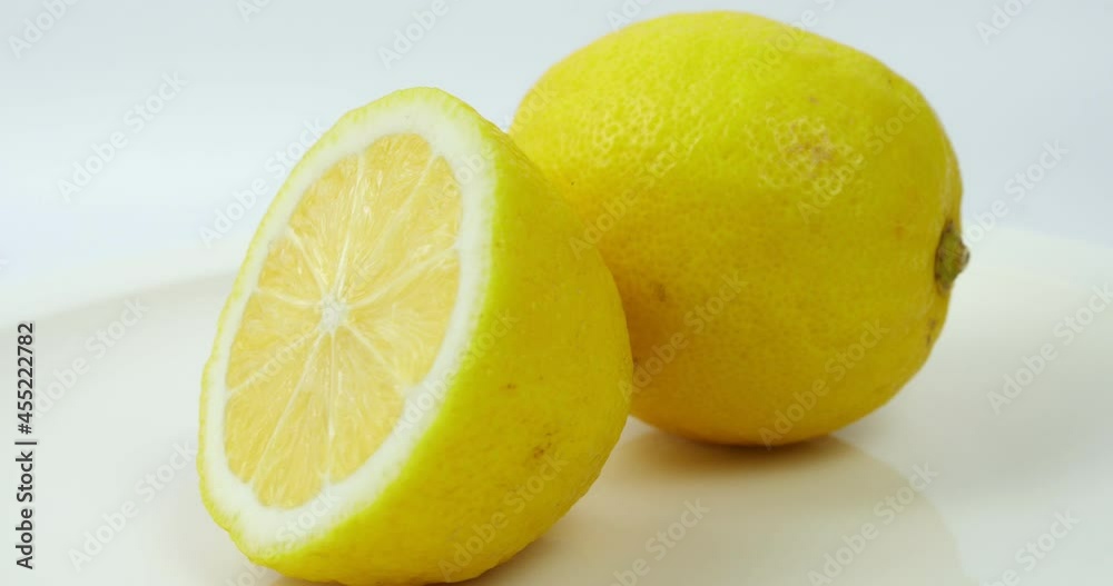 Group of ripe whole yellow lemon citrus fruit with lemon fruit half rotated on white background Group of ripe whole yellow lemon citrus fruit with lemon fruit half rotated on white background