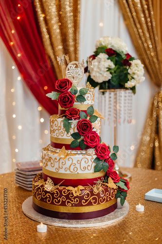 Beautiful festive cake decorated with red roses. Red and gold festive decoration