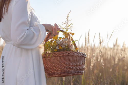 A woman holds a wooden basket with herbs in her hand. Place for text, copy-space