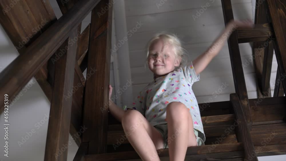 Happy child girl sitting on the wooden stairs in the house Happy child girl sitting on the wooden stairs in the house