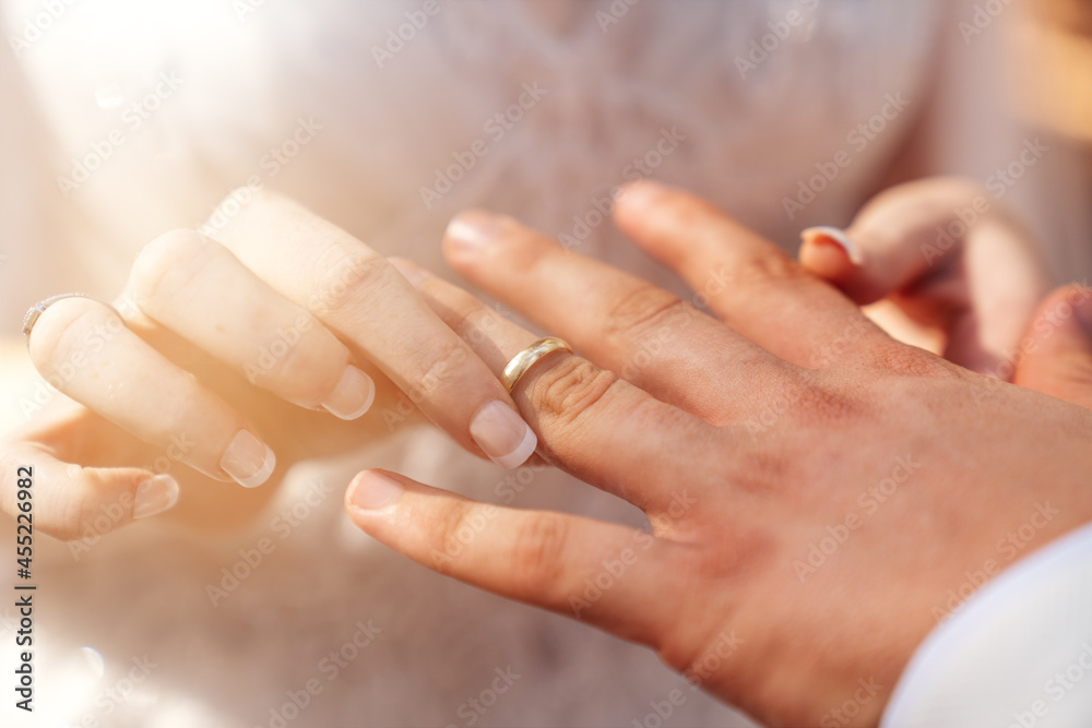 Bride and groom hands together and bride put wedding ring to grooms hand as a symbol of bonding