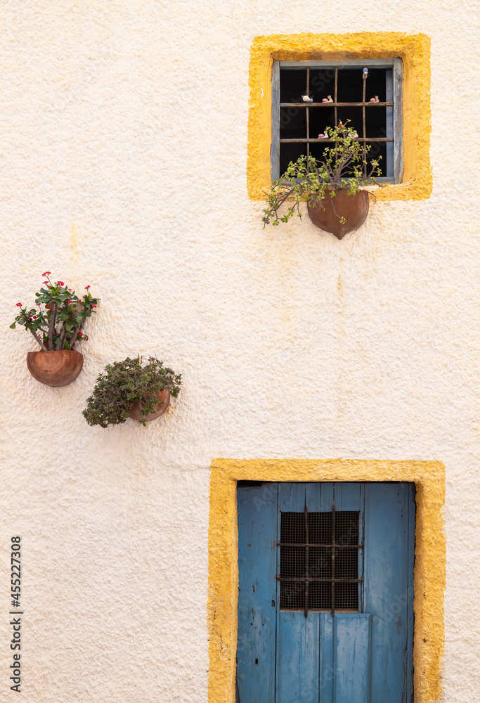 Windows with yellow frame, blue door and traditional Spanish flowerpots on white wall in Nijar, Andalusia, Spain