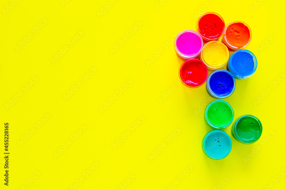 A creative flower made up of jars of paint on a yellow background with a place for text. top view, flat lay, copy space, isolate A creative flower made up of jars of paint on a yellow background with a place for text. top view, flat lay, copy space, isolate
