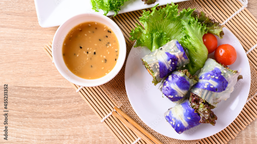 Vegan salad spring roll vegetable with edible flower eating with sesame sauce, Healthy Food, Table top view