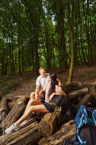 Happy young couple having rest while hiking in forest