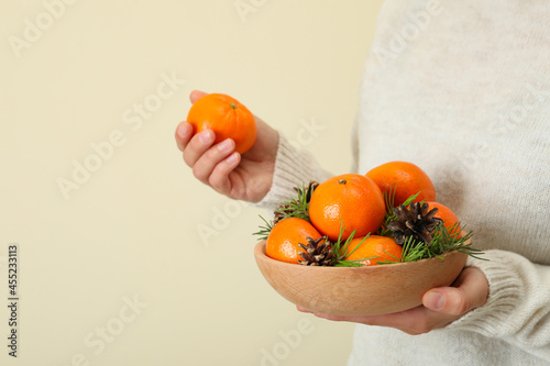 Woman in sweater holds bowl with mandarins, space for text