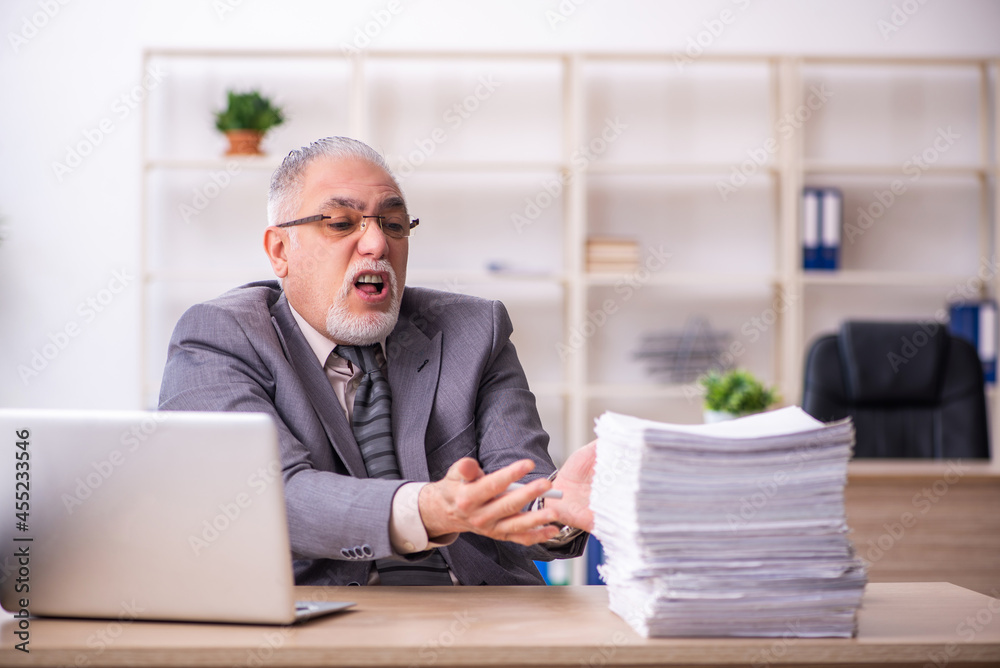 Old male employee working at workplace Old male employee working at workplace