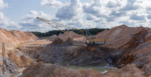 Boom walking excavator digs ilmenite ore in quarry photo
