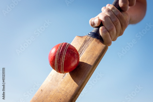 Cricket player batsman hitting a ball with a bat shot from below background