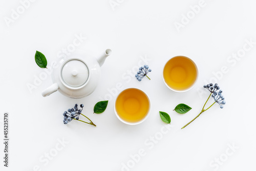 Two cups of tea with white teapot, top view