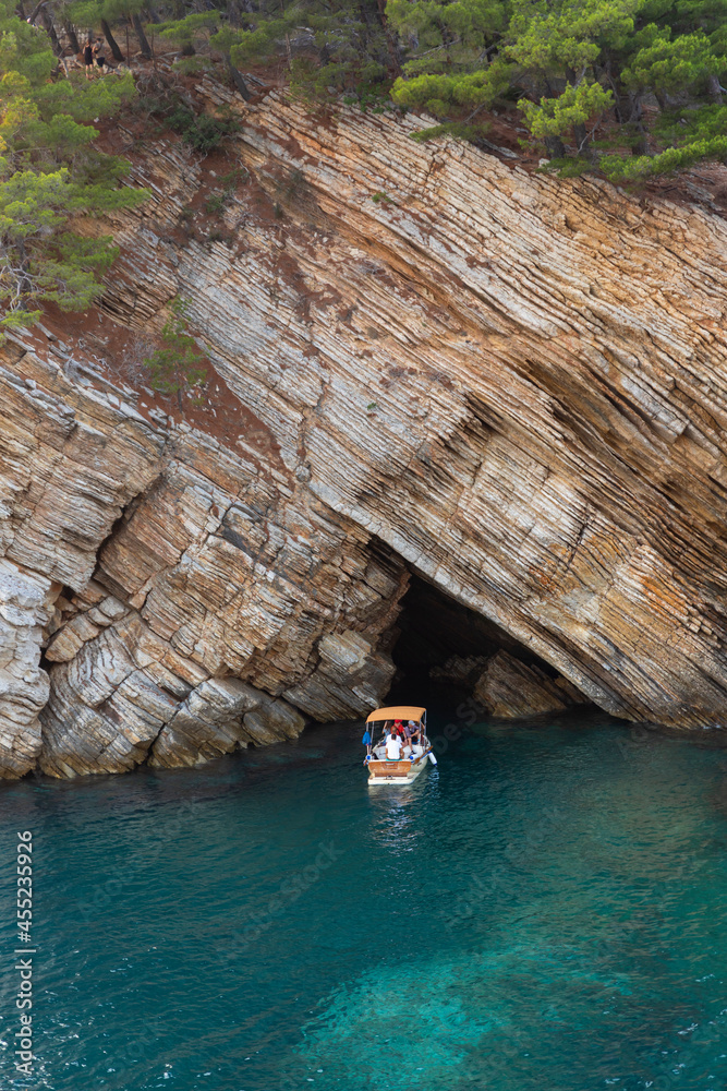 Fototapeta premium Tourist boat sailing at sea near the cave